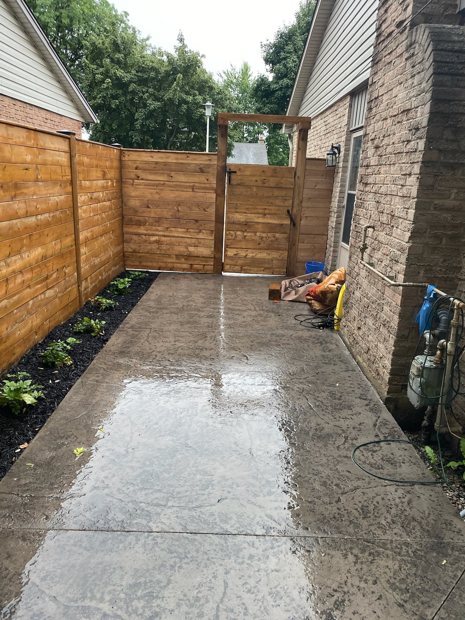 completed stamped concrete walkway from driveway to backyard through newly installed wooden gate