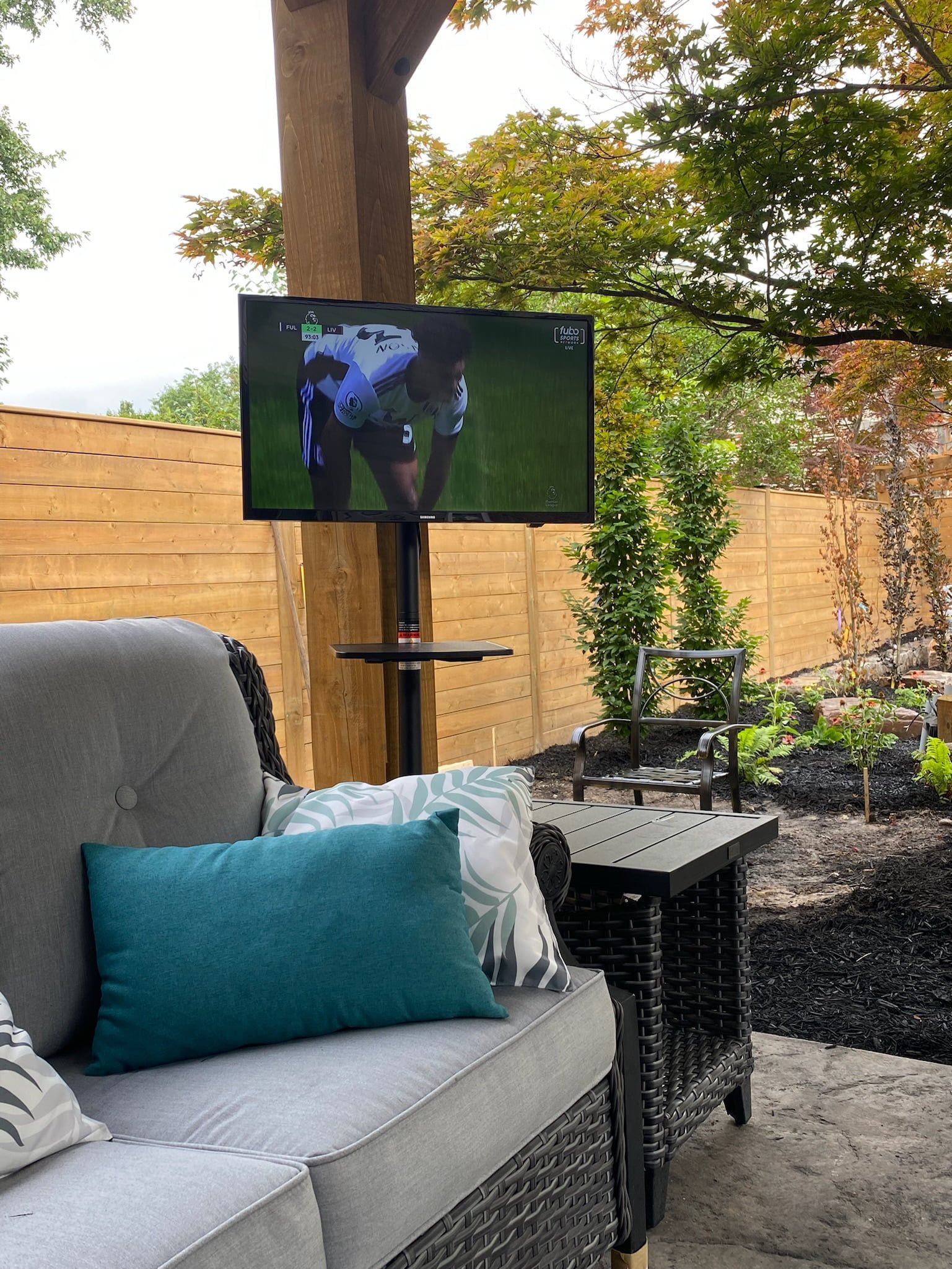 covered outdoor seating area by pool with tv during the day