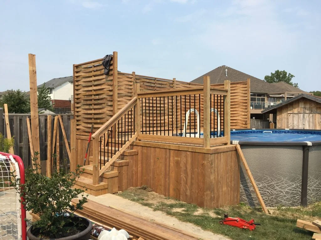 raised wooden deck around above ground pool with privacy screen