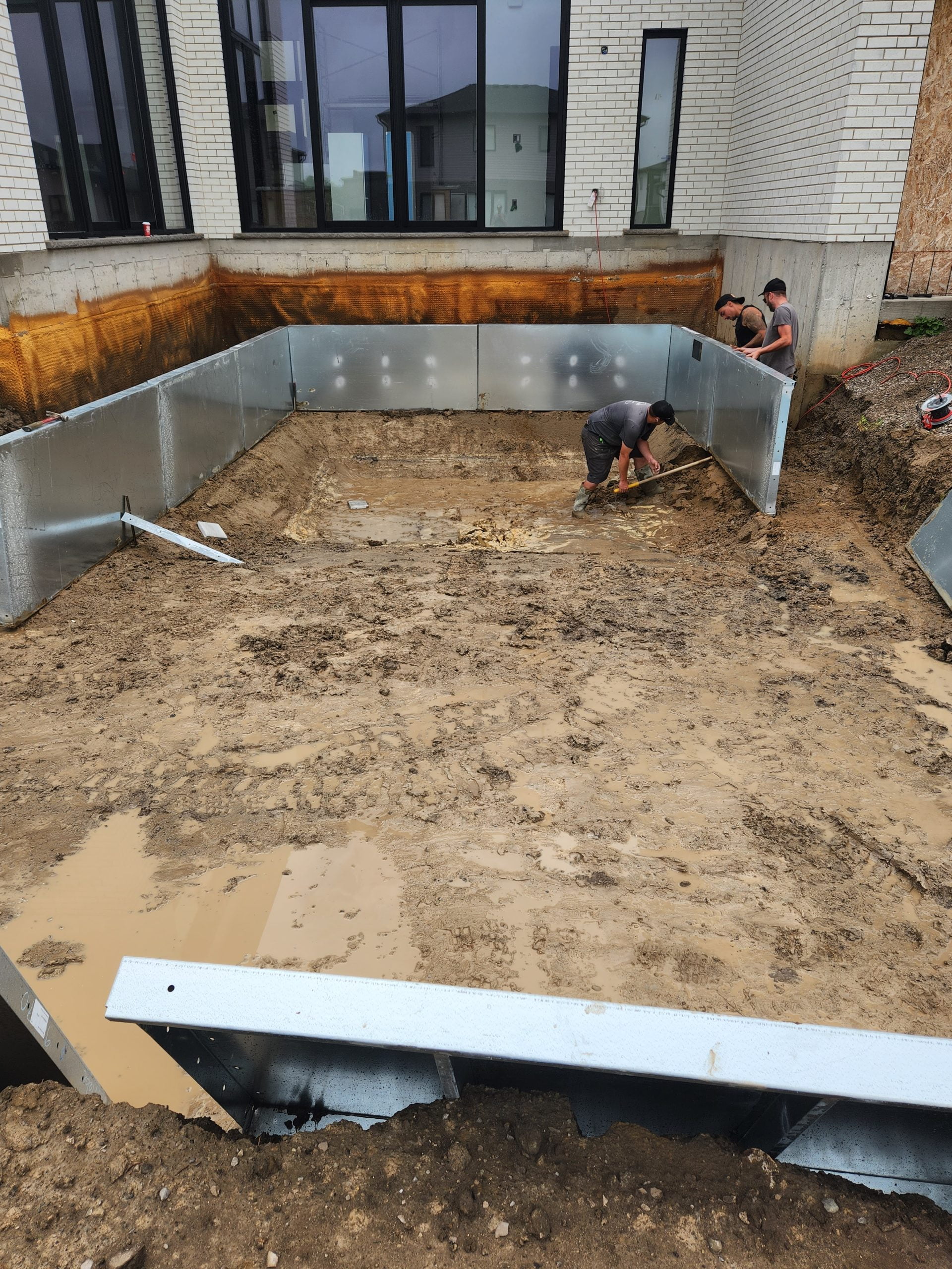 placing and setting pool walls for new inground pool installation after heavy rain