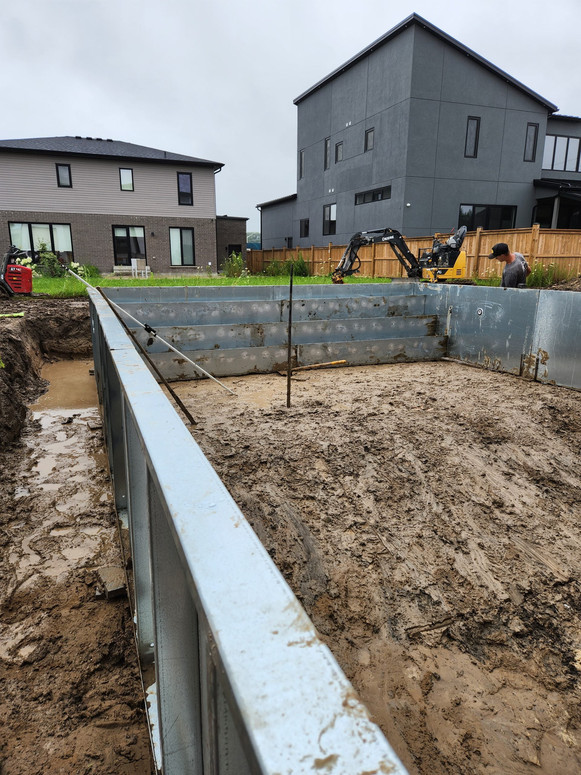 placing and setting steel pool stairs for new inground pool installation after heavy rain