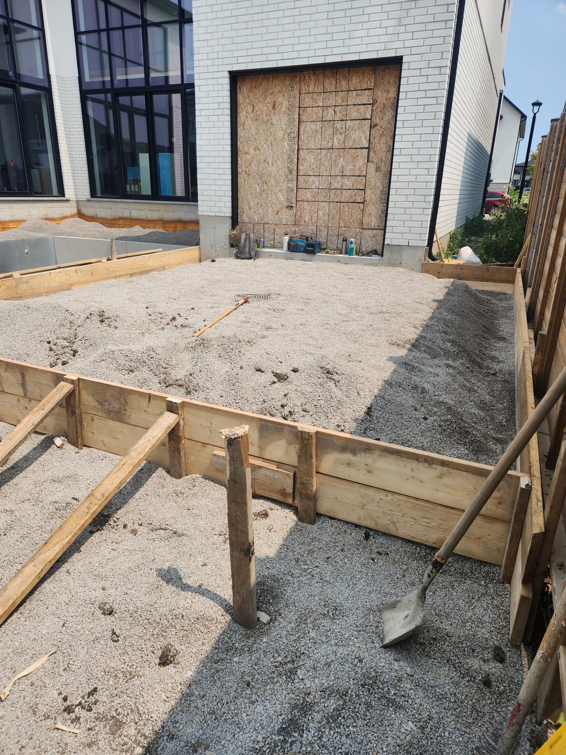 forming concrete patio area adding and tamping gravel
