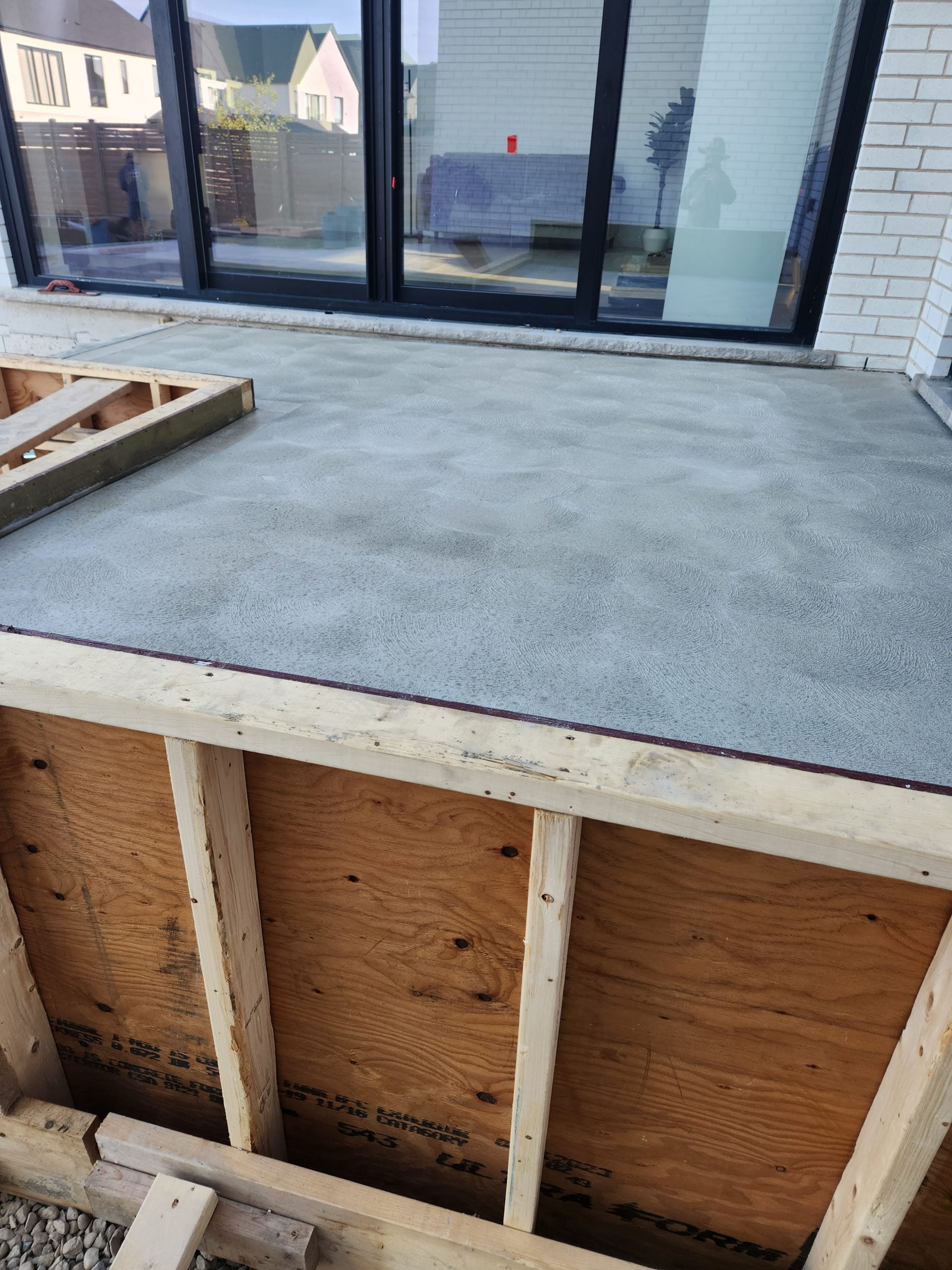 upper level of new multi-level raised concrete patio with a hand spun finish before forms removed