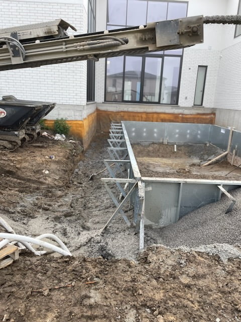 backfilling with gravel around pool wall panels, concrete footings and plumbing