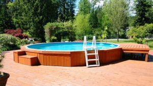 above ground pool with wooden retaining wall and deck and ladder